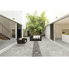 Terrasse mit grauen Bodenfliesen, Sitzmöbeln und Bepflanzung