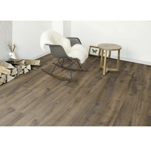 Innenraum mit Holzoptik-Bodenbelag, Schaukelstuhl mit Fell, Beistelltisch und Dekoration.