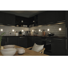 Helle Küche mit schwarzen Küchenschränken, Fliesen und Beleuchtung.