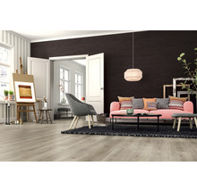 Wohnzimmer mit hellbraunem Laminatboden, rosa Sofa und Staffelei.