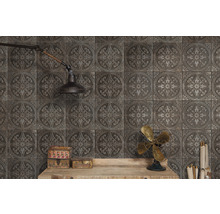 Wandgestaltung mit quadratischen Fliesen mit floralem Muster und rustikalem Flair, ergänzt durch eine Wandlampe und dekorative Elemente auf einem Holztisch.