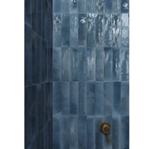 Badezimmerwand mit länglichen, rechteckigen Fliesen und einem Duschkopf