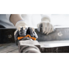 Person mit Handschuhen schleift Werkstück mit Schleifklotz