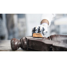 Eine Person schleift ein Holzobjekt mit einem Schleifpad der Marke Bosch, Körnung mittel.