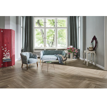 Heller Wohnraum mit Sofa, Sessel, Raumteiler und Fischgrätparkett