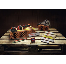 Maurerwerkzeugsortiment auf Holzpalette mit Bandmaßen, Messrad, Gliedermaßstäben, Bleistiften und Digitaluhr