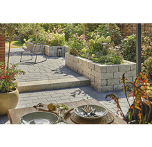 Gestalteter Garten mit Pflastersteinen, Sitzgelegenheit und erhöhten Pflanzbeeten