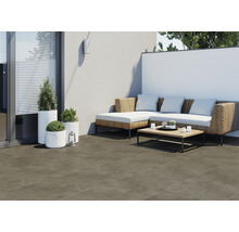 Terrasse mit Bodenfliesen, Rattansofa, Couchtisch und Pflanzenkübeln