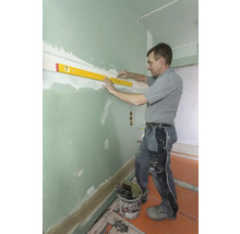 Handwerker richt Wand mit Wasserwaage aus.