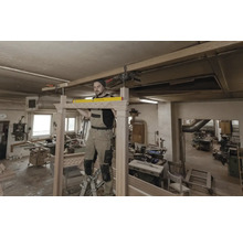 Handwerker montiert Holzkonstruktion mit Wasserwaage in Werkstatt