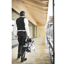 Ein Mann trägt eine Paneelsäge auf einer Baustelle.