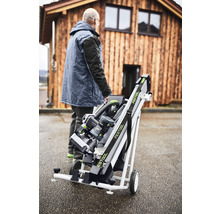 Mann transportiert Festool Tisch mit Rollen vor einem Holzhaus.