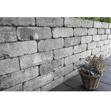 Graue Gartenmauer aus Betonsteinen mit Pflanzenkorb
