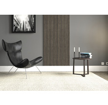 Wohnzimmer mit Sessel, Wandpaneel, Beistelltisch, Büchern, Kerzen und Teppich