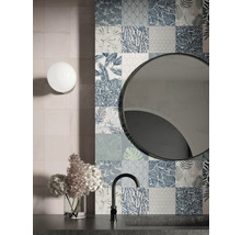 Badezimmer mit Wandfliesen in Patchwork-Optik, rundem Spiegel und Armatur