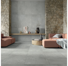 Wohnzimmer mit grauen Bodenfliesen und Wandfliesen in Steinoptik.