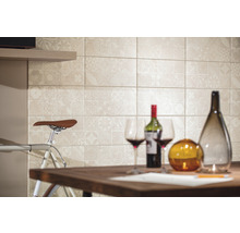 Dekorative Fliesenwand hinter einem Tisch mit Weinflasche und Gläsern.