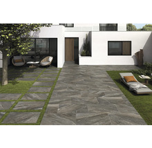 Moderne Gartengestaltung mit Terrassenplatten und Rasenflächen vor einem weißen Haus