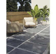 Terrassengestaltung mit grauen Steinplatten, weißen Zierkieseln, zwei Sesseln, Holzzaun und Pflanzen