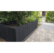 Gartenszene mit Hochbeet aus Betonsteinen und gepflastertem Weg