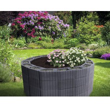 Hochbeet aus Betonsteinen mit Blumen in einem Garten.