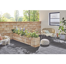 Gestalteter Außenbereich mit Mauer, Pflanzkästen, Sitzgelegenheiten und Bodenbelag.