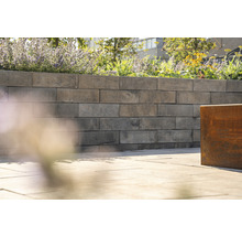 Eine Gartenmauer aus Betonsteinen mit Blumen bepflanzt