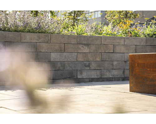 Eine Gartenmauer aus Betonsteinen mit Blumen bepflanzt