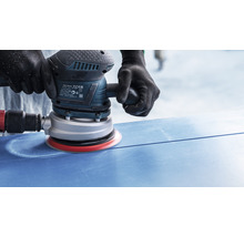 Eine Person schleift eine blaue Oberfläche mit einem Exzenterschleifer.