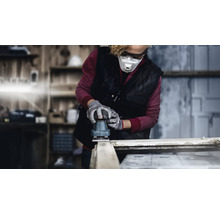 Eine Person schleift mit einem Exzenterschleifer ein Holzstück. Die Person trägt Schutzbrille, Atemschutzmaske und Handschuhe.