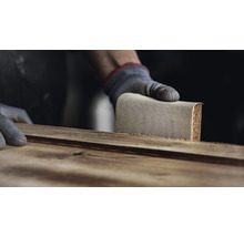 Eine Person schleift ein Holzbrett mit einem Schleifklotz