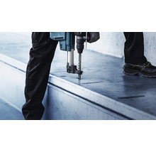 Eine Person bohrt mit einem Bohrhammer in eine Betonoberfläche.