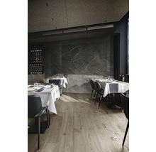 Restaurant mit Holzboden, Tischen mit weißen Tischdecken und schwarzen Stühlen