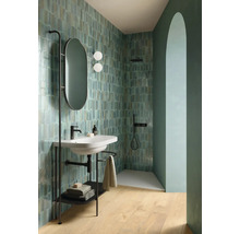 Badezimmer mit Waschbecken auf einem Metallgestell, ovalem Spiegel und gefliesten Wänden