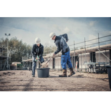 Zwei Bauarbeiter arbeiten mit Schaufel und Mörtelrührer auf einer Baustelle.
