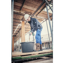 Handwerker mischt Mörtel mit einem elektrischen Rührer auf einem Gerüst.