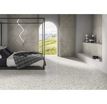 Helles Schlafzimmer mit Terrazzoboden, Bett und Blick auf die Natur