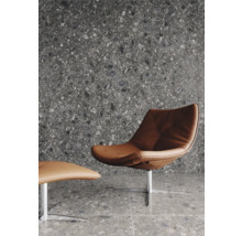 Modernes Wohnzimmer mit Sessel und Fußhocker auf grauem Terrazzoboden