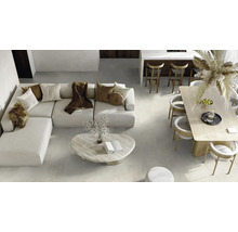 Ansicht eines Wohnzimmers mit Sofa, Tisch und Stühlen auf einem hellen Fliesenboden.