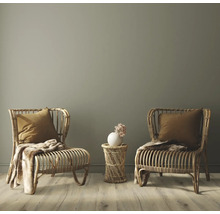 Zwei Rattansessel mit Kissen und Decken sowie ein Beistelltisch mit Blumenvase in einem hellen Raum.