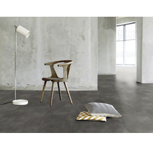 Innenraum mit Stuhl, Stehlampe und Kissen auf grauem Boden