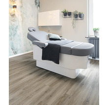 Behandlungszimmer mit Liege, Schrank, Pflanzen und Holzboden