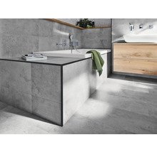 Helles Badezimmer mit Badewanne, Waschtisch und grauen Fliesen.