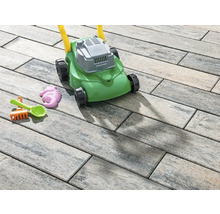 Spielzeugrasenmäher und Sandspielzeug auf Pflastersteinen