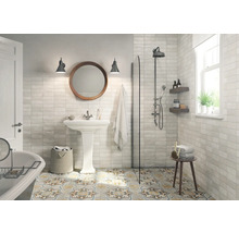 Helles Badezimmer mit Dusche, Waschbecken, Spiegel und gemusterten Bodenfliesen.