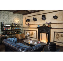 Dekoratives Wohnzimmer mit blauem Ledersofa, Bücherregal und Kamin