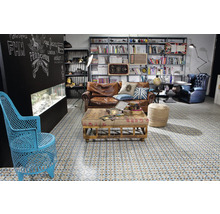 Wohnzimmer mit braunem Ledersofa, Couchtisch, Bücherregal und gemustertem Fliesenboden.