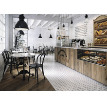 Helles Café mit Tischen, Stühlen und einer Theke mit Gebäckauslage