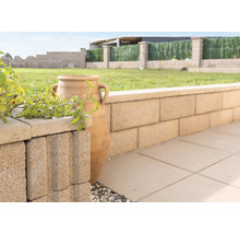 Gartenmauer aus Betonsteinen mit dekorativer Amphore und Pflanzen