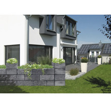 Garten mit Mauer aus Betonsteinen und Bepflanzung vor einem Wohnhaus